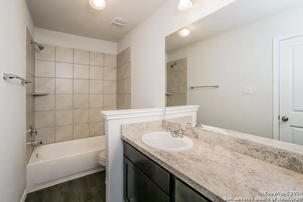 a bathroom with a granite countertop tub sink and mirror