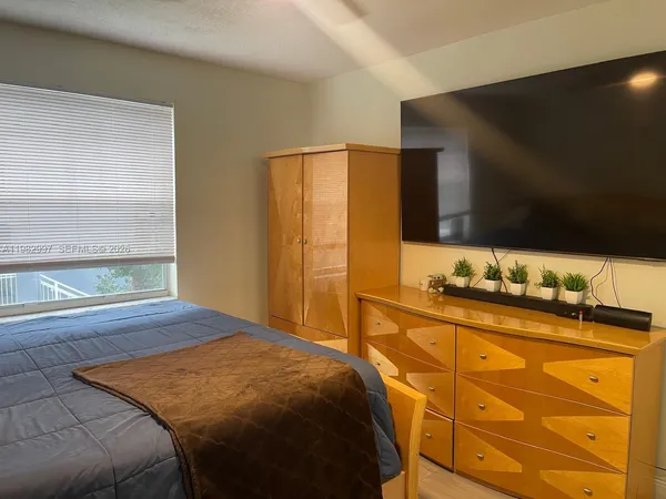a bedroom with a bed and a flat tv screen on dresser