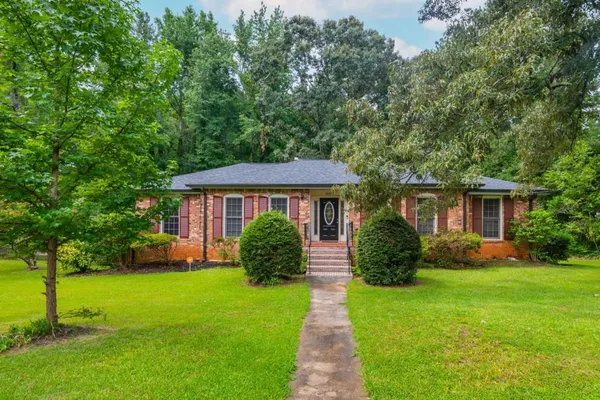 a front view of a house with a yard and trees