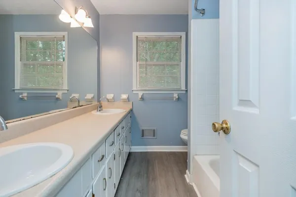 a bathroom with a sink a toilet a tub and a window