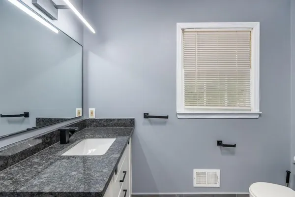 a bathroom with a granite countertop sink and a mirror