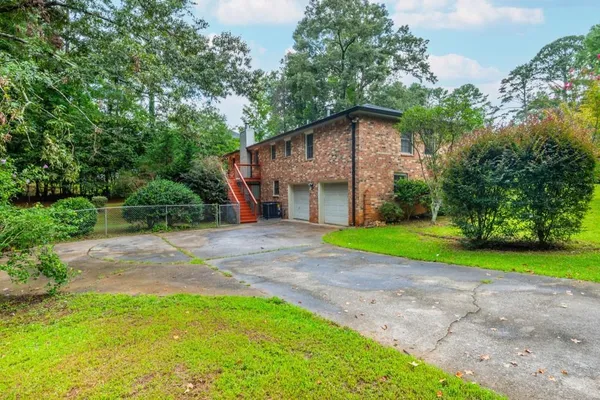 a view of a house with a yard and large trees