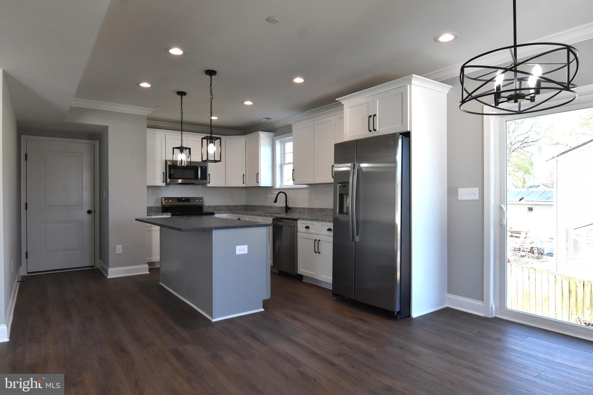 7704 Highpoint Road Clearwater Beach, MD 21226 - Photo 5 of 48 a kitchen with stainless steel appliances granite countertop a refrigerator a sink dishwasher a stove and a dining table with wooden floor