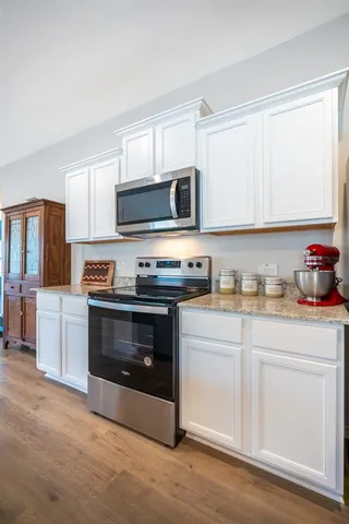 a kitchen with granite countertop white cabinets and stainless steel appliances
