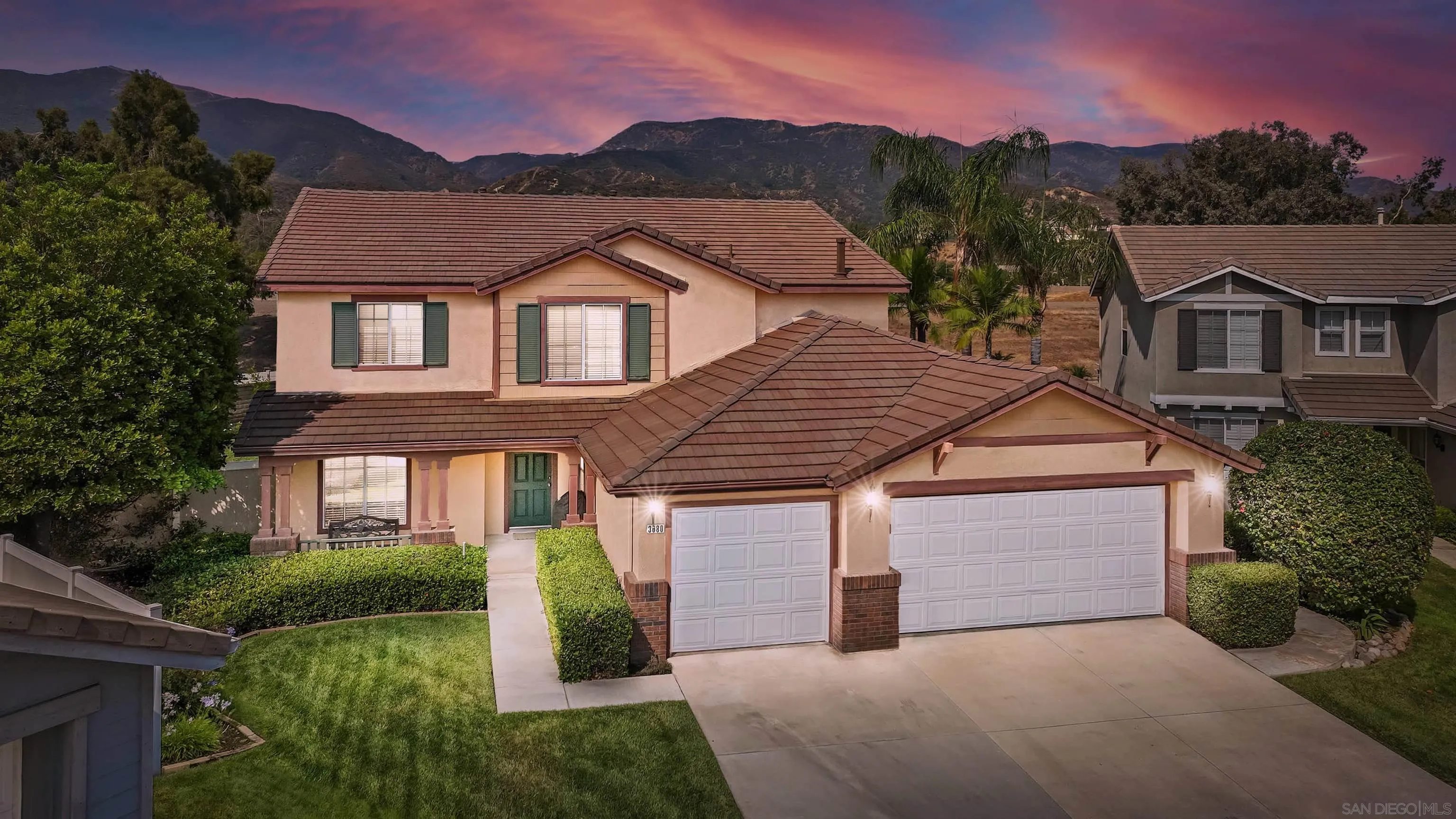 a front view of a house with a garden and mountain view