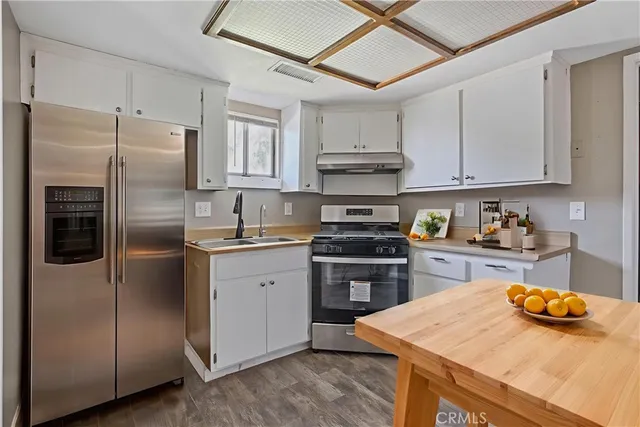 a kitchen with stainless steel appliances a refrigerator a sink a stove and white cabinets