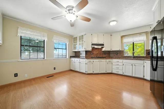 a view of empty room with wooden floor and fan
