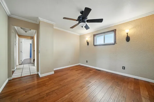an empty room with wooden floor ceiling fan and window