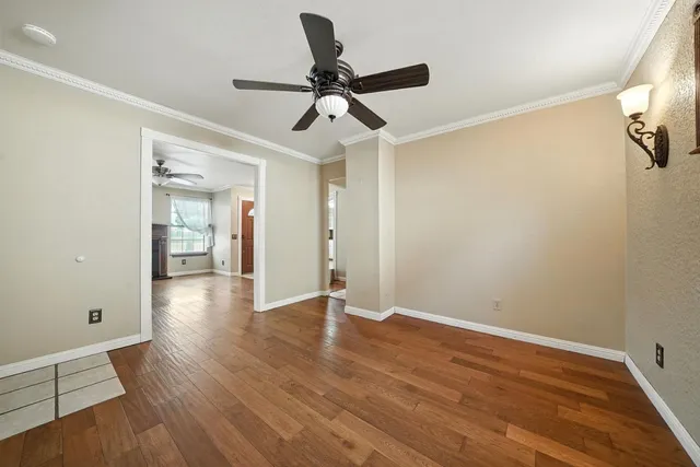 an empty room with wooden floor ceiling fan and windows