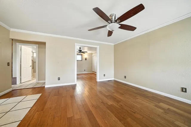 a view of an empty room with a window and wooden floor