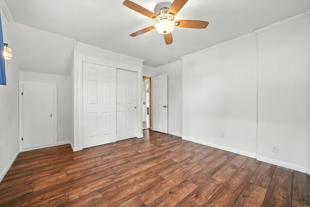 an empty room with wooden floor and a ceiling fan