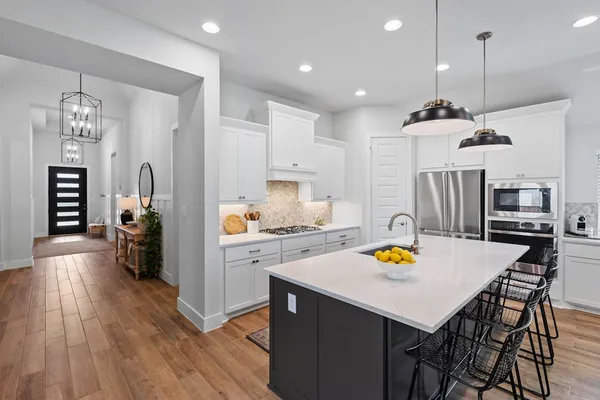 a kitchen with stainless steel appliances a dining table chairs and wooden floor