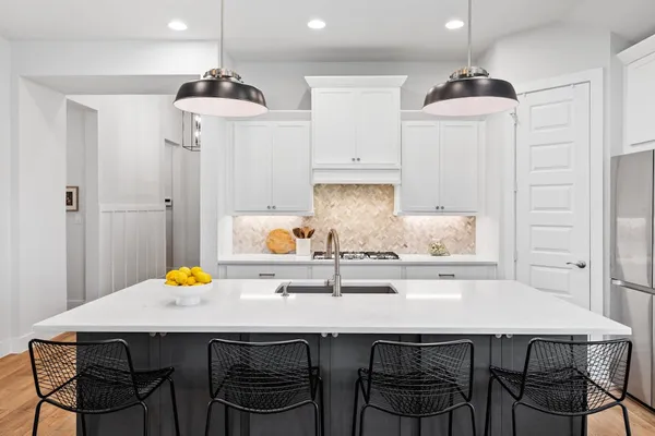 a kitchen with stainless steel appliances a dining table chairs and white cabinets