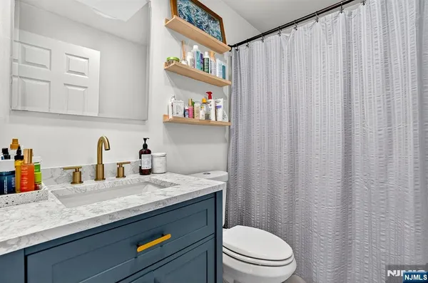 a bathroom with a granite countertop sink vanity mirror and toilet