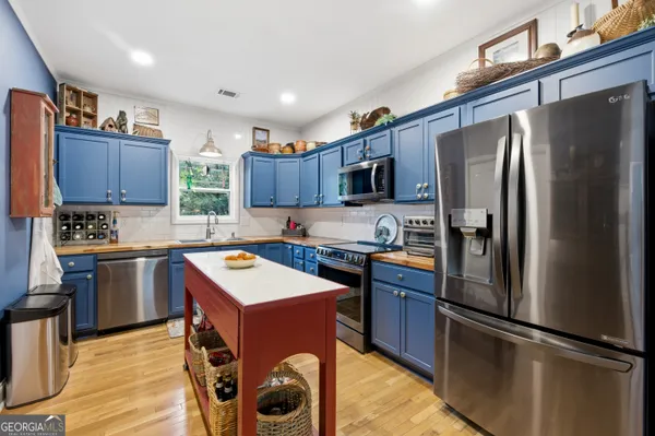 a kitchen with kitchen island granite countertop stainless steel appliances cabinets a sink and a refrigerator