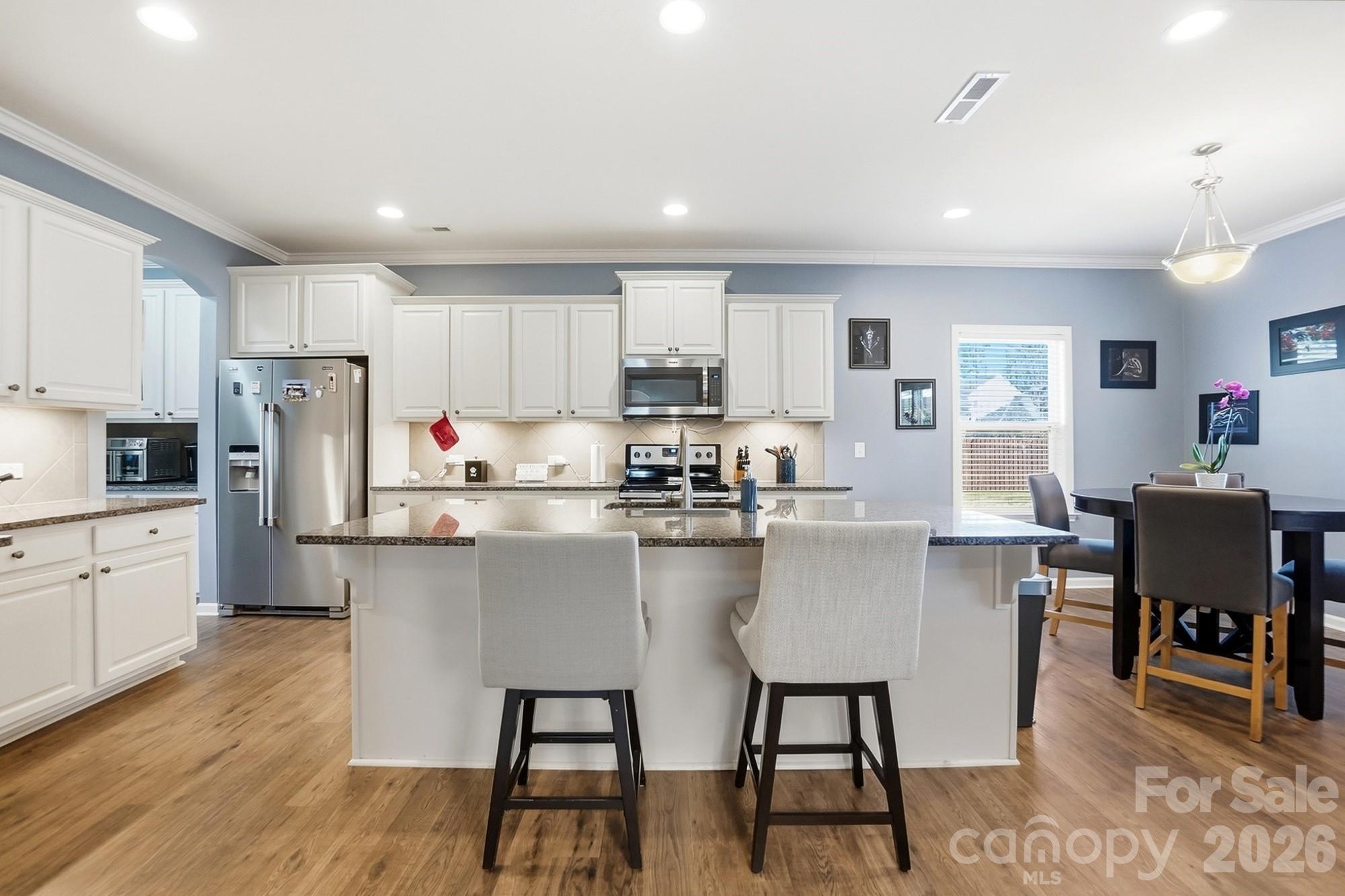 1103 Clover Lane Matthews, NC 28104 - Photo 8 of 46 a kitchen with stainless steel appliances granite countertop a stove a sink a microwave a dining table and chairs