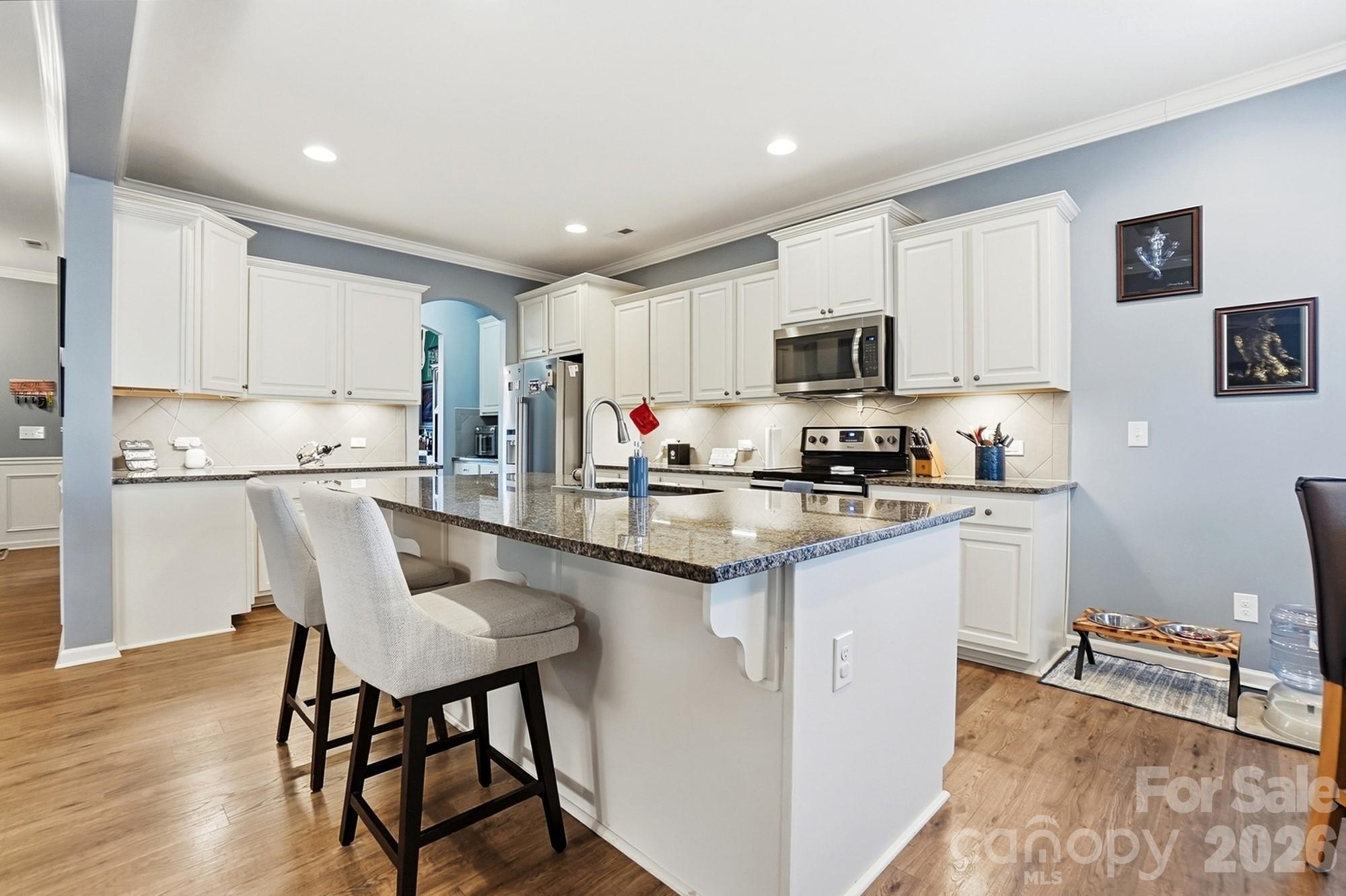 1103 Clover Lane Matthews, NC 28104 - Photo 9 of 46 a kitchen with granite countertop a stove a sink a dining table and chairs