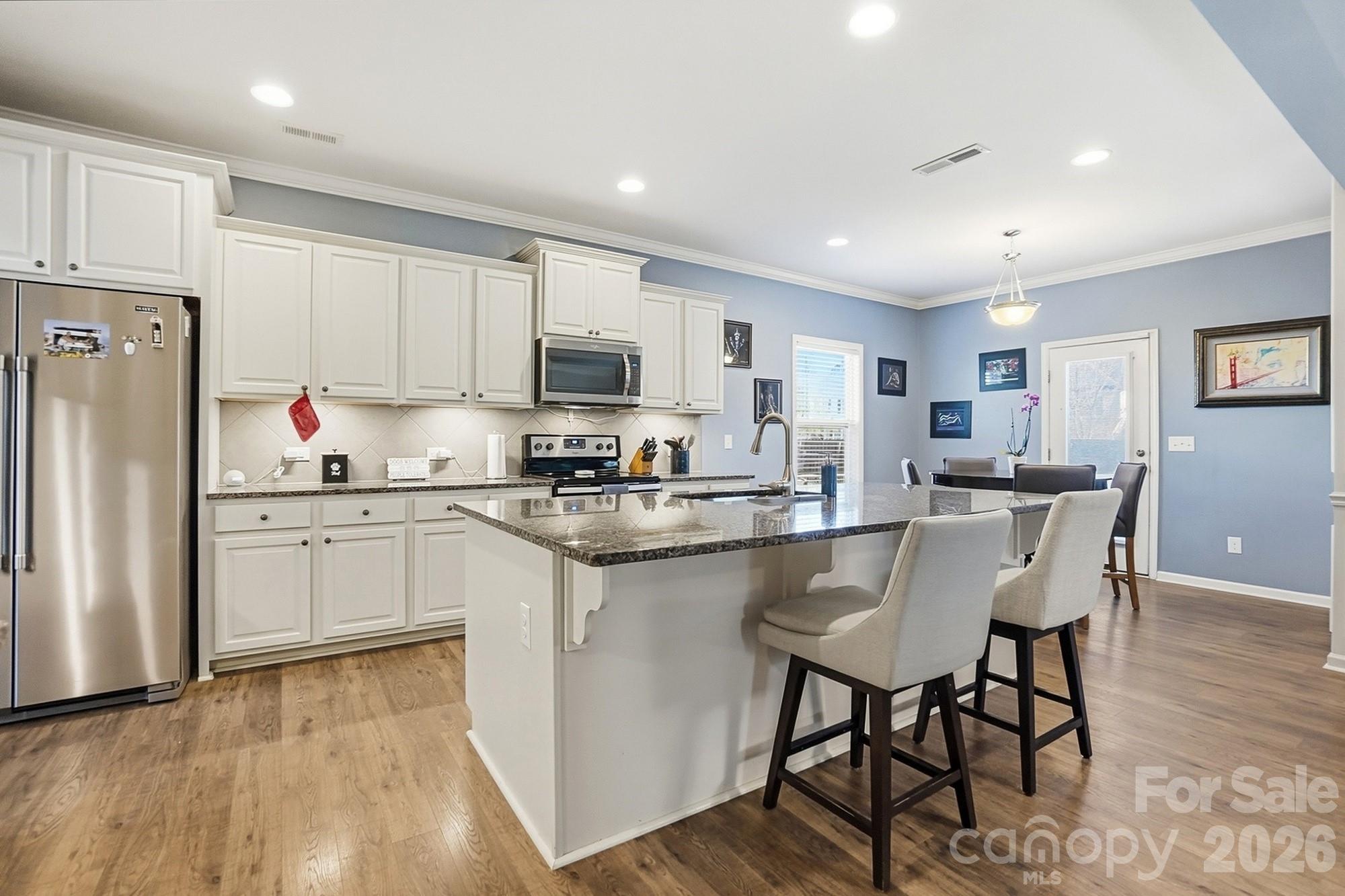 1103 Clover Lane Matthews, NC 28104 - Photo 10 of 46 a kitchen with stainless steel appliances granite countertop a stove a sink a refrigerator with a dining table and chairs