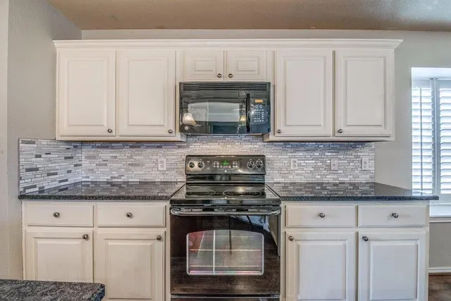 a kitchen with granite countertop white cabinets and stainless steel appliances