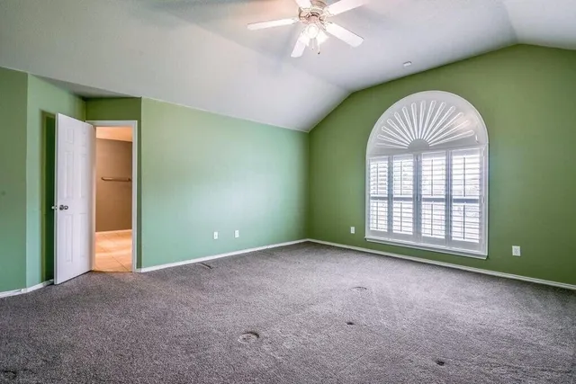 an empty room with windows and chandelier fan