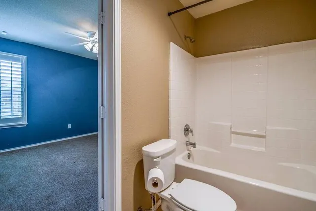 a white toilet sitting next to a bath tub and a shower