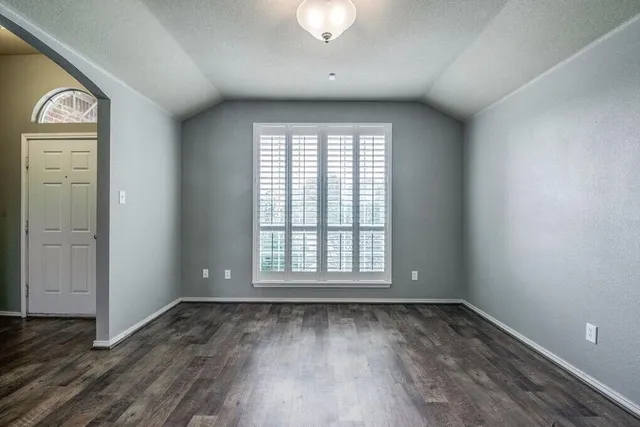 an empty room with a window and wooden floor