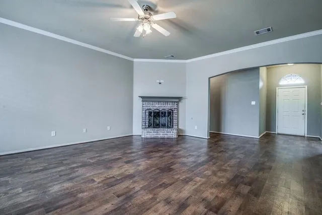 a view of an empty room with a fireplace and a chandelier fan