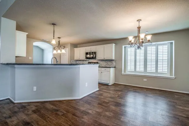 a view of a kitchen with granite countertop stove top oven and cabinets