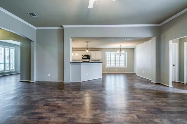 a view of an empty room with window and wooden floor
