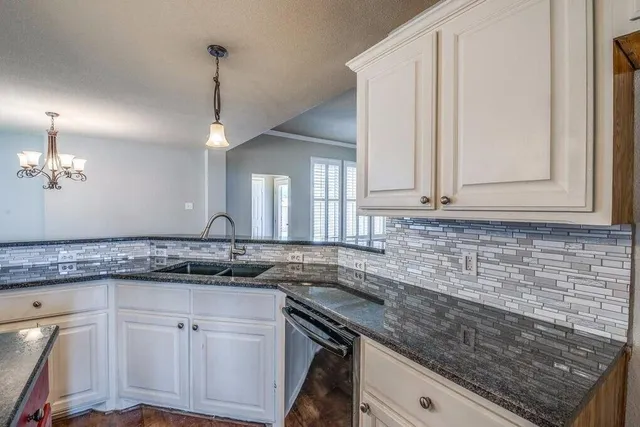 a kitchen with granite countertop a sink a counter space appliances and cabinets