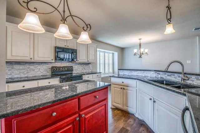 a kitchen with granite countertop a sink a counter space cabinets and stainless steel appliances