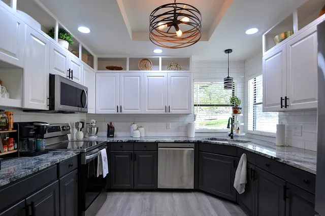 a kitchen with granite countertop a sink a window and cabinets