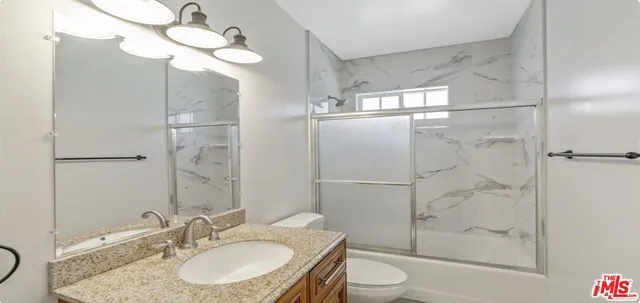 a bathroom with a granite countertop sink toilet a mirror and shower