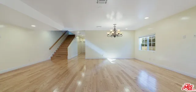 wooden floor in an empty room with a chandelier