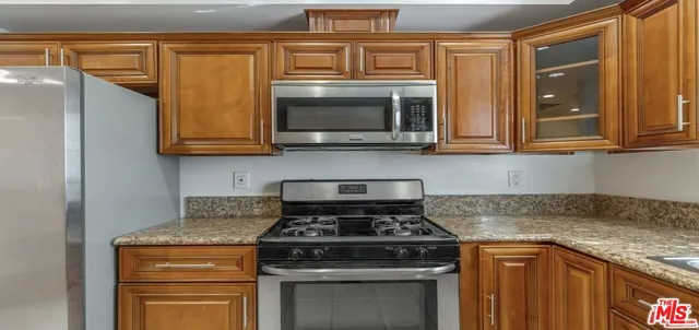a kitchen with granite countertop a stove top oven microwave and cabinets