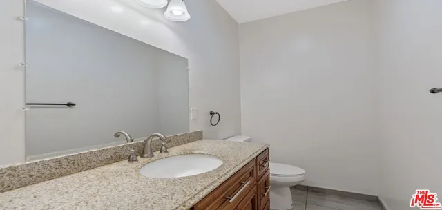 a bathroom with a granite countertop sink a mirror and a toilet