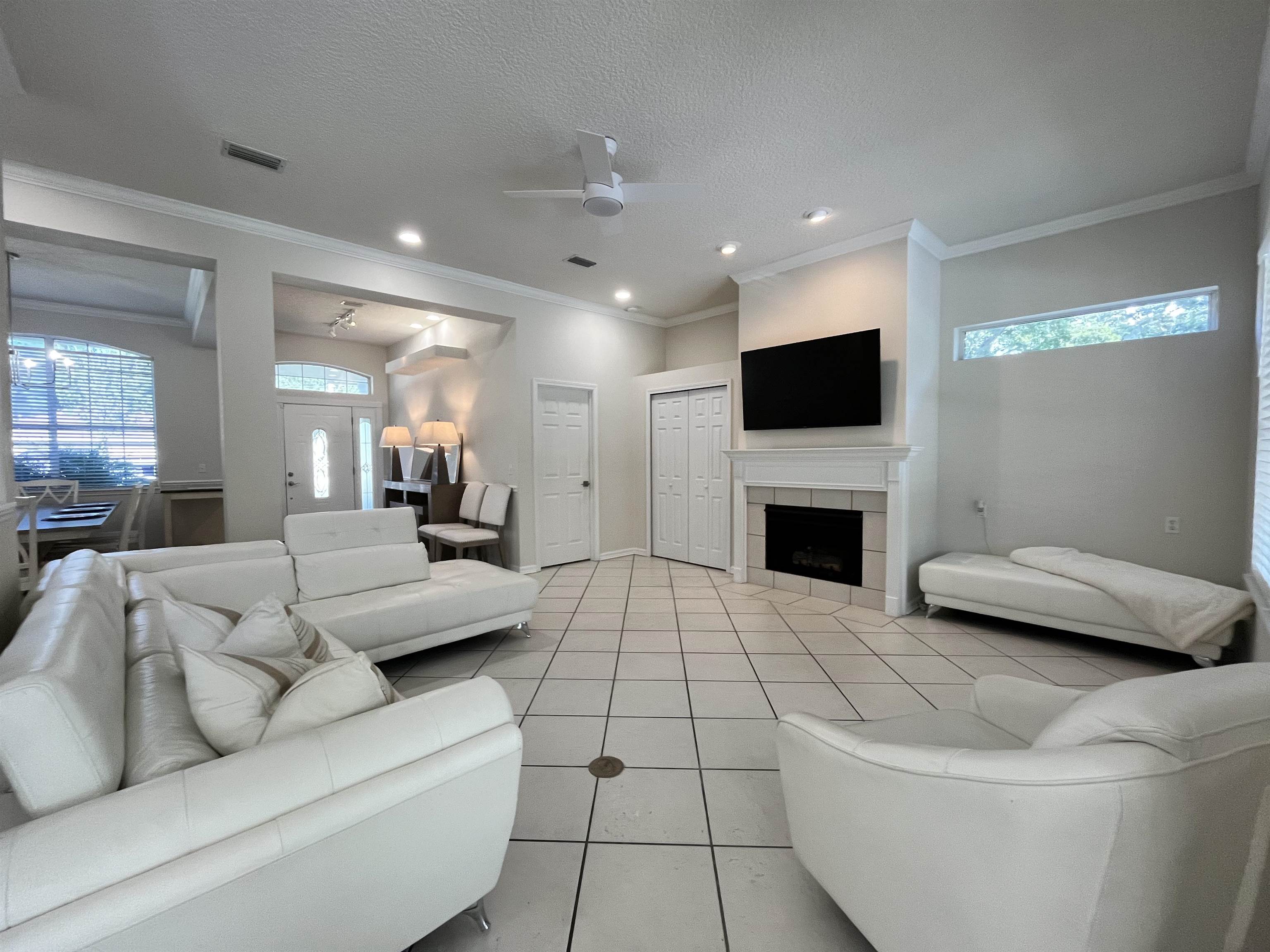 9606 Melvina Road Jacksonville, FL 32257 - Photo 11 of 23 Living area with tile patterned flooring, ornamental molding, ceiling fan, a textured ceiling, and a tiled fireplace
