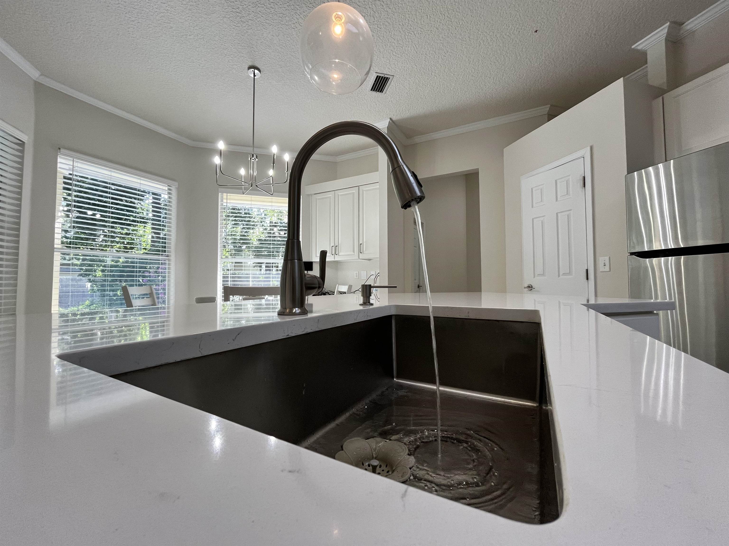 9606 Melvina Road Jacksonville, FL 32257 - Photo 12 of 23 Kitchen with a textured ceiling, crown molding, light stone counters, freestanding refrigerator, and a chandelier