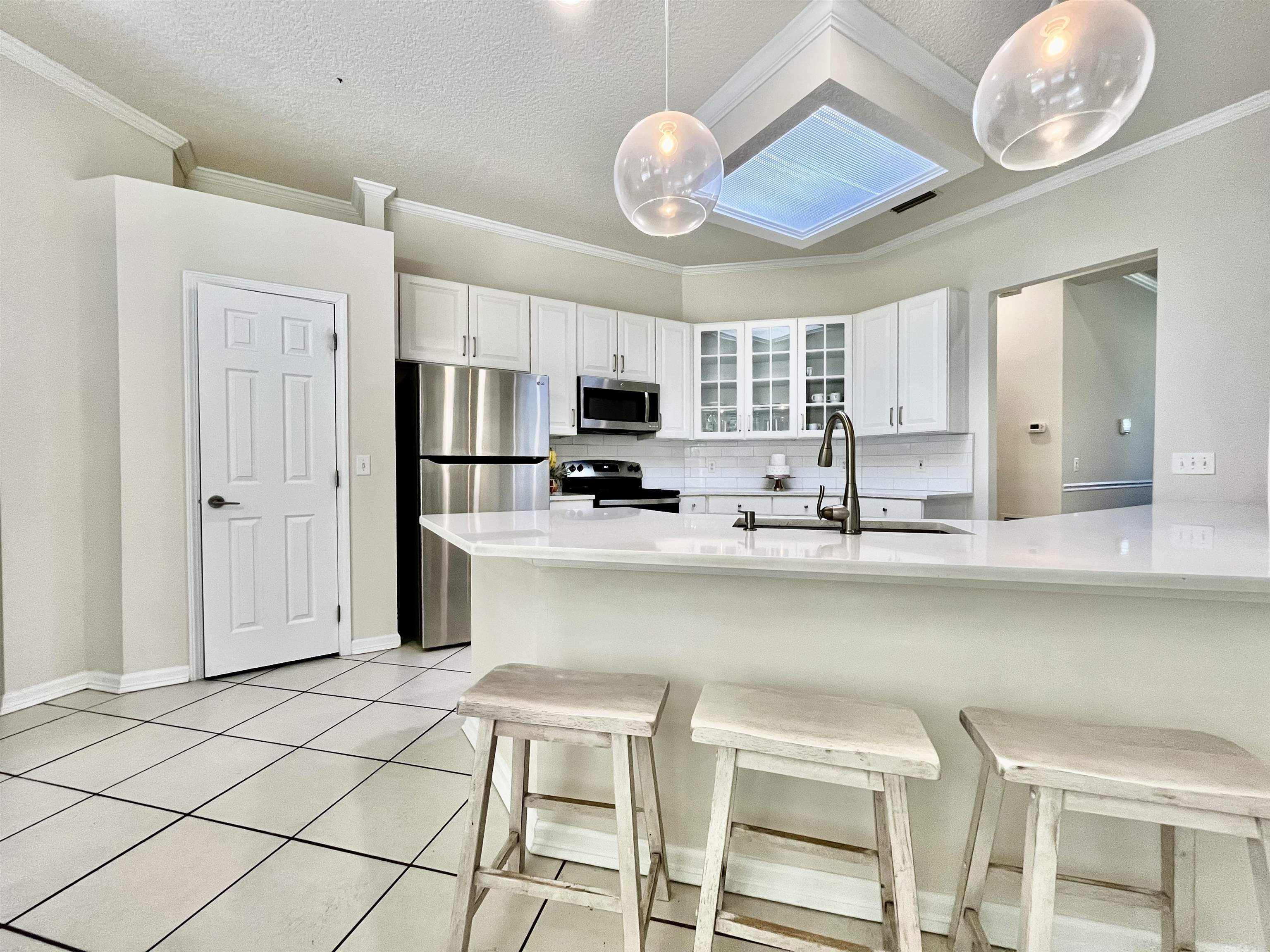 9606 Melvina Road Jacksonville, FL 32257 - Photo 14 of 23 Kitchen featuring glass insert cabinets, appliances with stainless steel finishes, a breakfast bar area, white cabinetry, and a textured ceiling