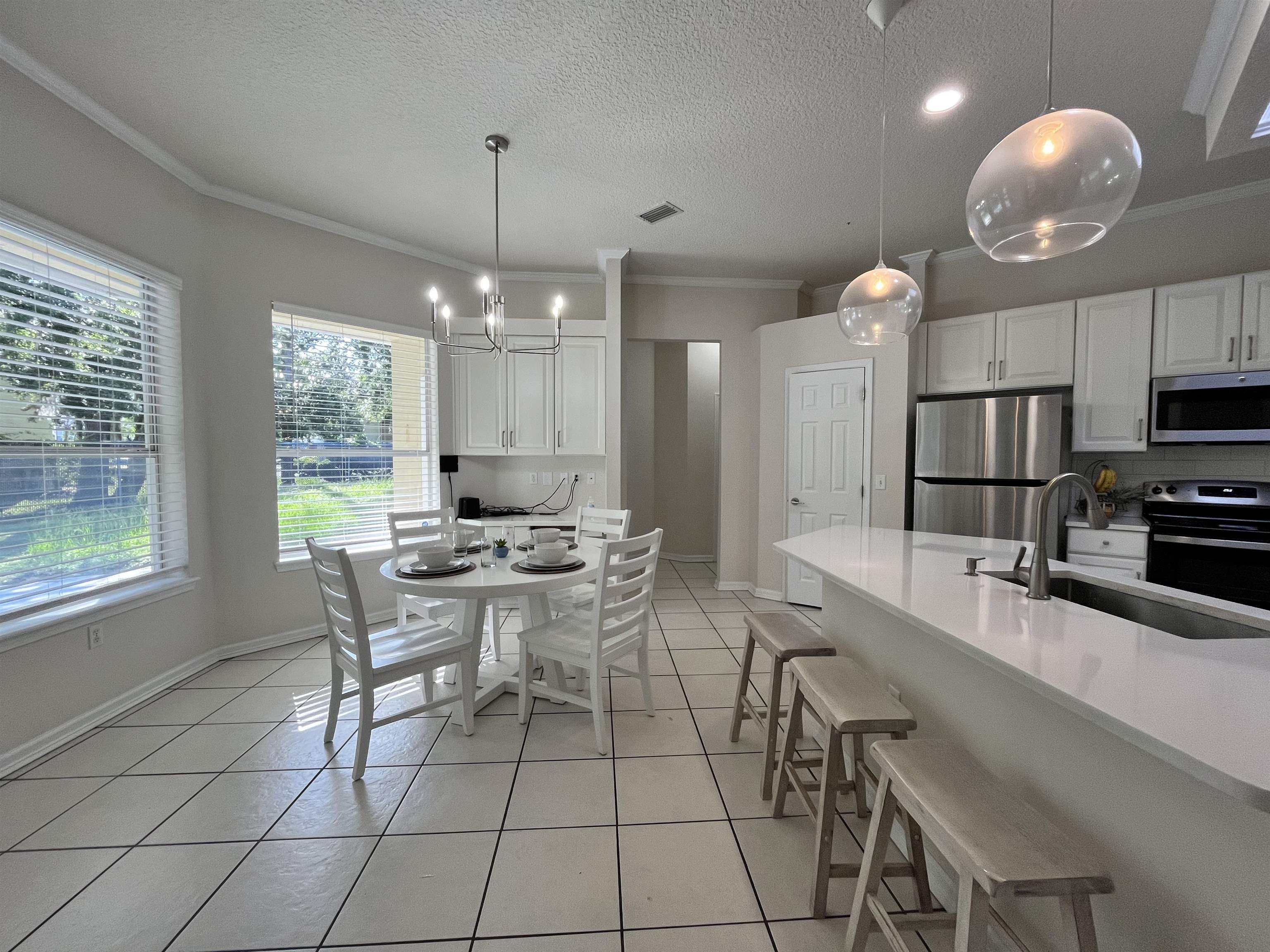 9606 Melvina Road Jacksonville, FL 32257 - Photo 15 of 23 Dining room with a textured ceiling, ornamental molding, light tile patterned floors, and a chandelier