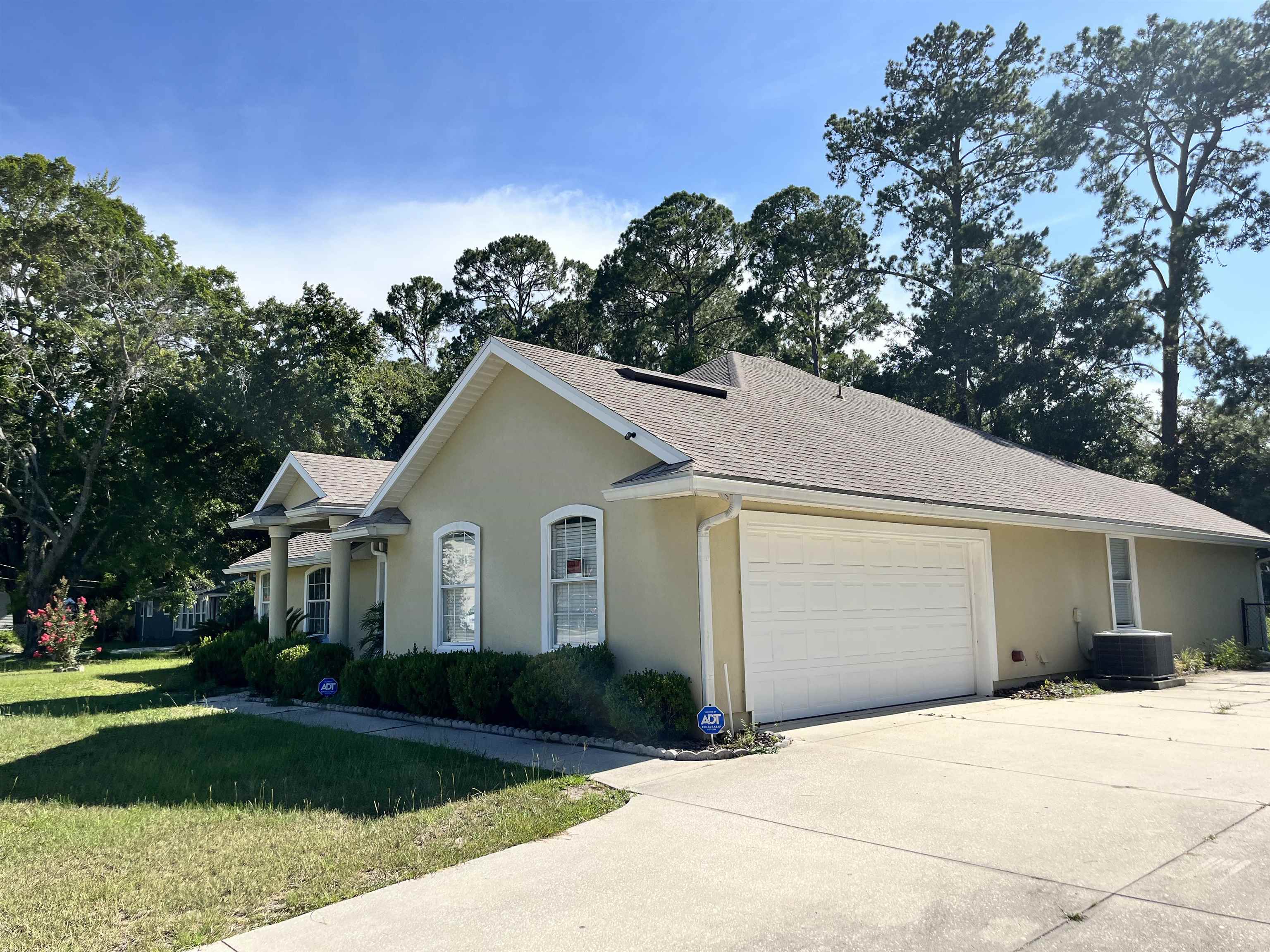 9606 Melvina Road Jacksonville, FL 32257 - Photo 20 of 23 View of side of home with roof with shingles, a lawn, stucco siding, a garage, and concrete driveway