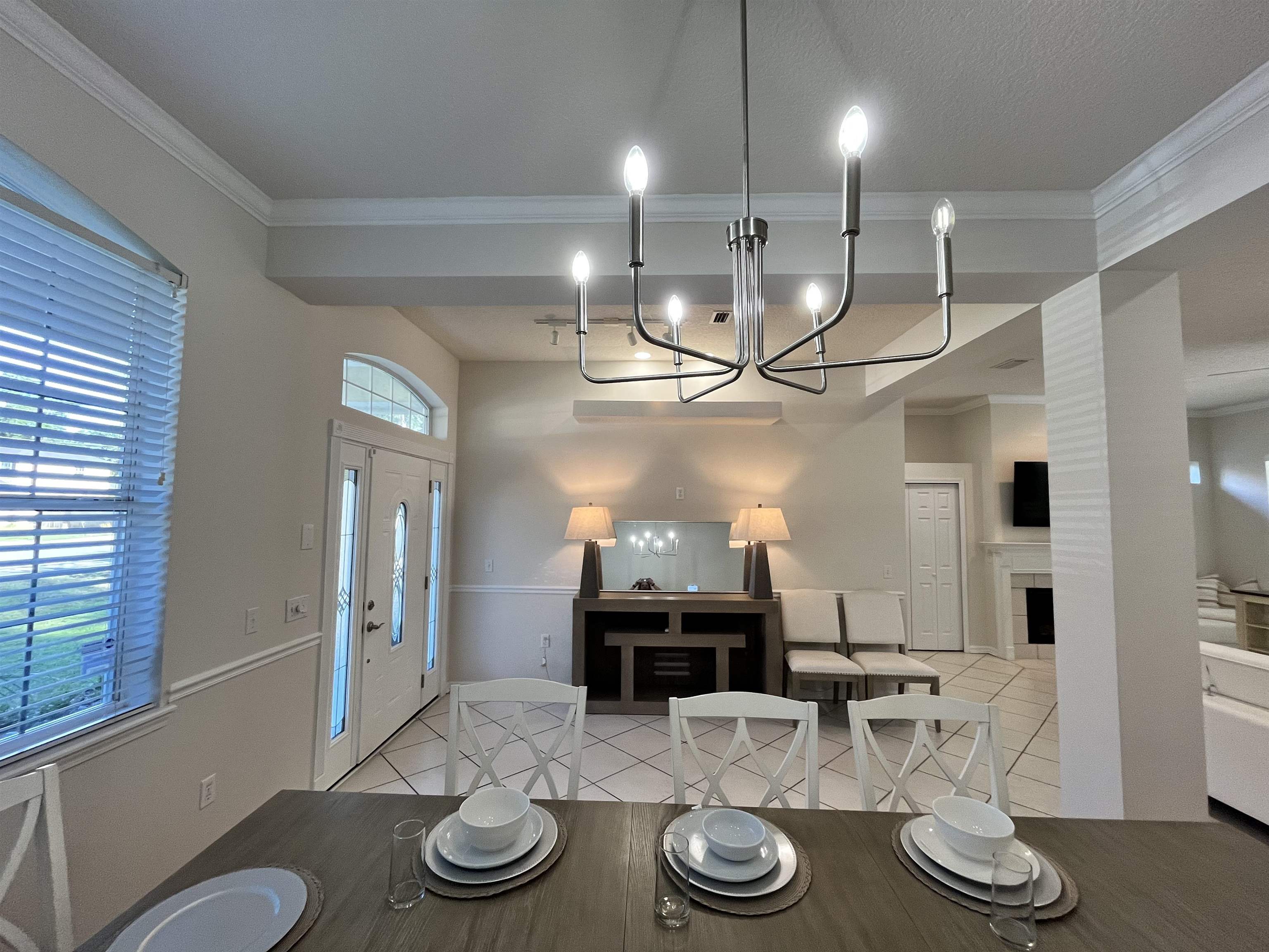 9606 Melvina Road Jacksonville, FL 32257 - Photo 5 of 23 Dining area featuring a fireplace, light tile patterned flooring, ornamental molding, and a chandelier