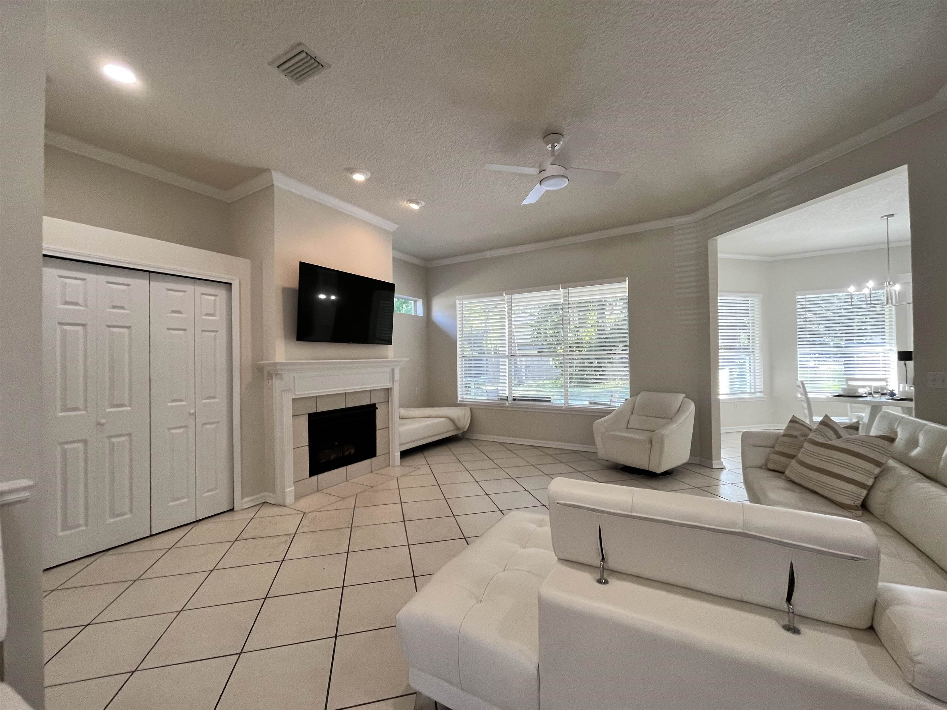 9606 Melvina Road Jacksonville, FL 32257 - Photo 8 of 23 Living area with light tile patterned floors, ornamental molding, a textured ceiling, a ceiling fan, and a chandelier