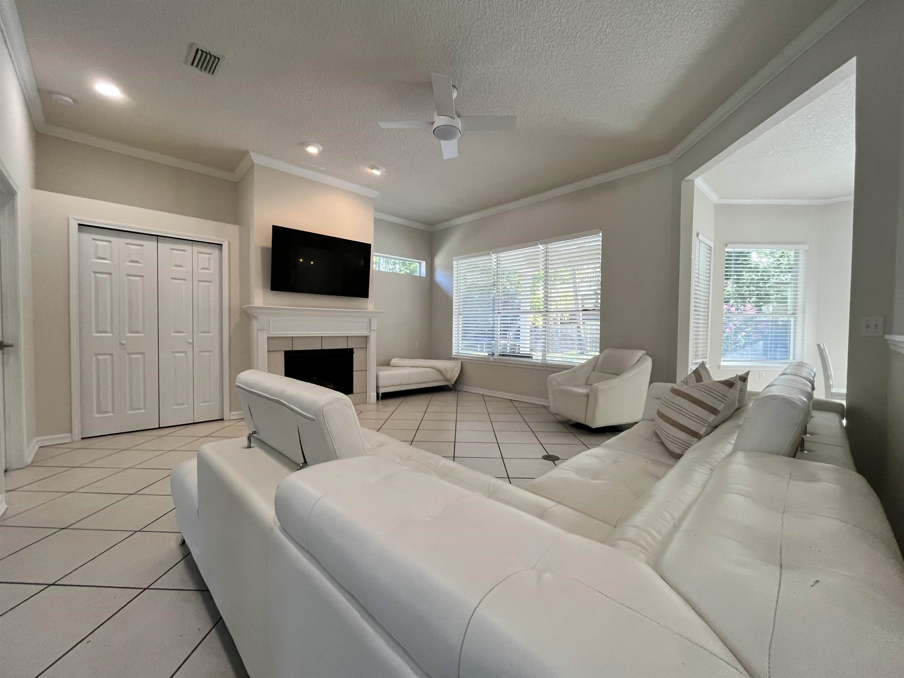 9606 Melvina Road Jacksonville, FL 32257 - Photo 10 of 23 Living area featuring light tile patterned floors, crown molding, ceiling fan, a textured ceiling, and a fireplace