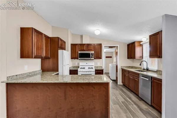 a kitchen with stainless steel appliances granite countertop a sink stove microwave and refrigerator