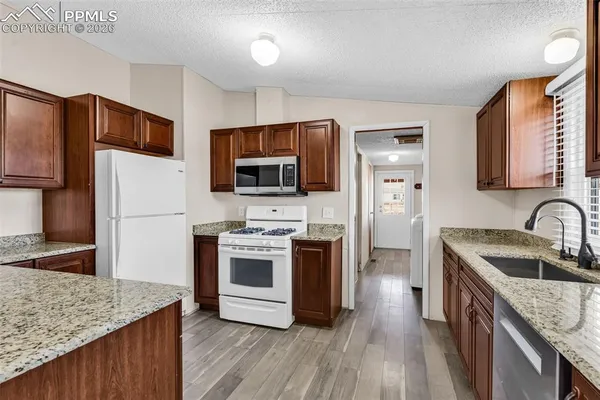 a kitchen with stainless steel appliances granite countertop a stove a sink dishwasher and a refrigerator