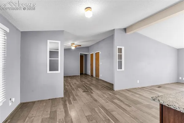 a view of an empty room with a window and wooden floor