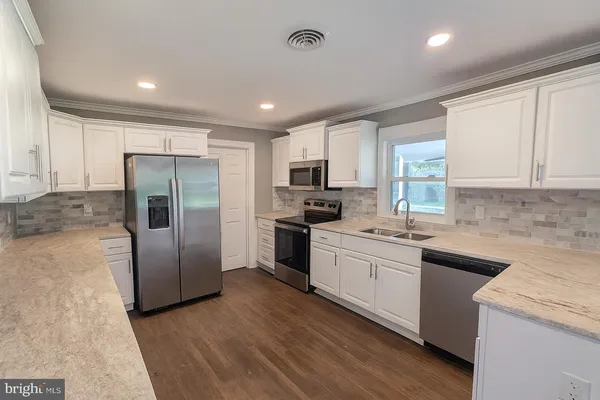 a kitchen with a sink a refrigerator a microwave and cabinets
