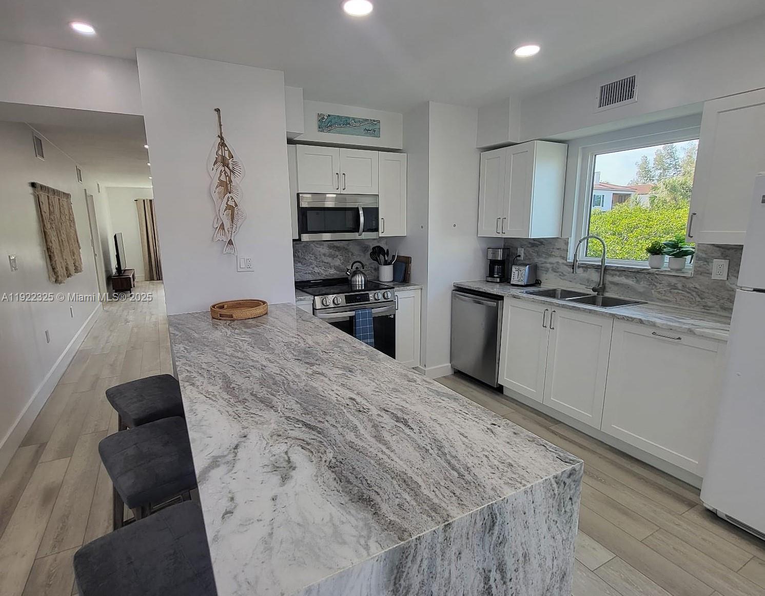 3320 Gulf Of Mexico Drive, Unit 208C Longboat Key, FL 34228 - Photo 9 of 39 a kitchen with stainless steel appliances kitchen island granite countertop a sink stove and refrigerator