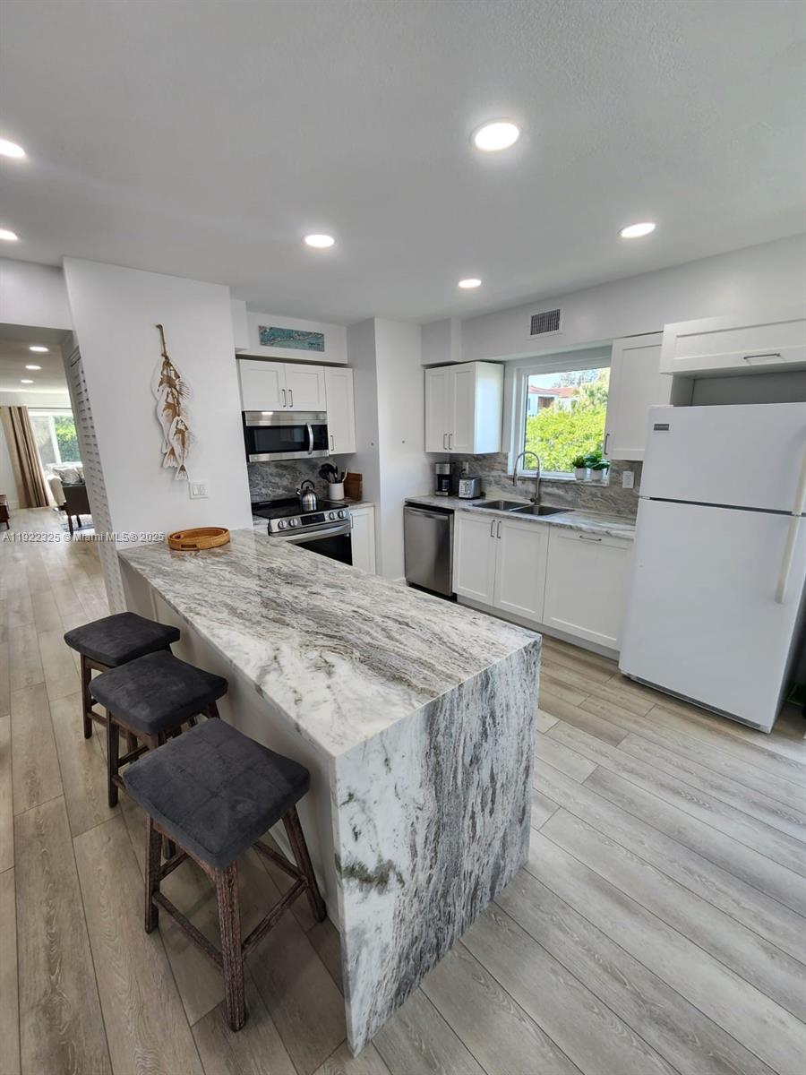 3320 Gulf Of Mexico Drive, Unit 208C Longboat Key, FL 34228 - Photo 10 of 39 a large kitchen with kitchen island a stove a table and a refrigerator